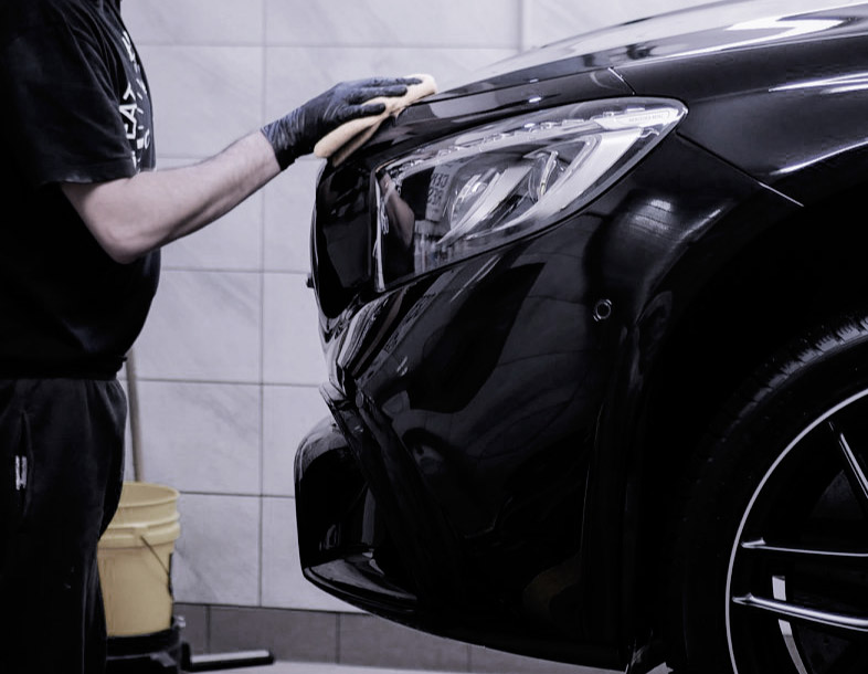 Detailer wykańcza przedni zderzak czarnego Mercedesa